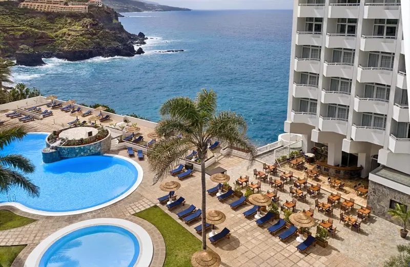 Vue aérienne d'un complexe hôtelier avec piscine et accès à la mer.