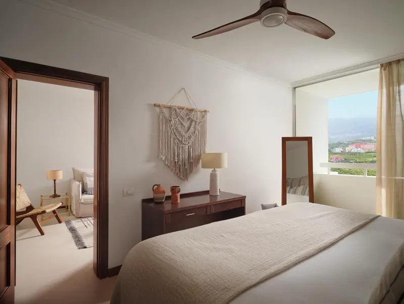 Une chambre lumineuse avec un lit et un espace salon attenant.