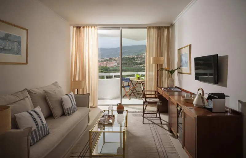 Espace de vie lumineux avec canapé et vue sur la mer depuis une terrasse.