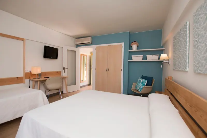 Une chambre lumineuse avec un lit blanc et un mur bleu.