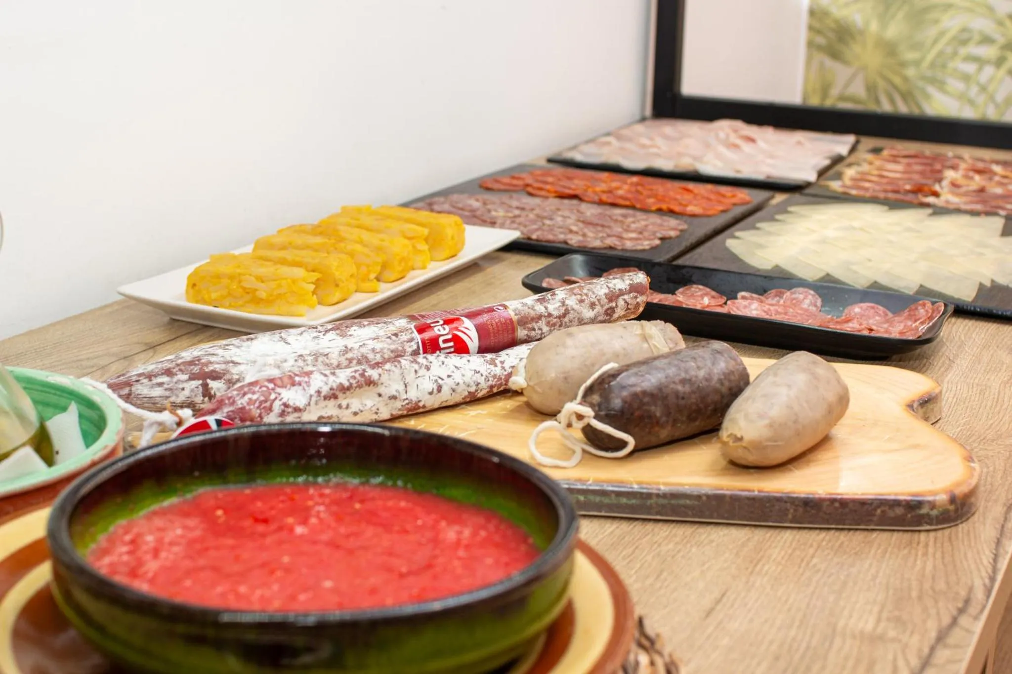 Présentation de charcuteries et de fromages sur un comptoir en bois.