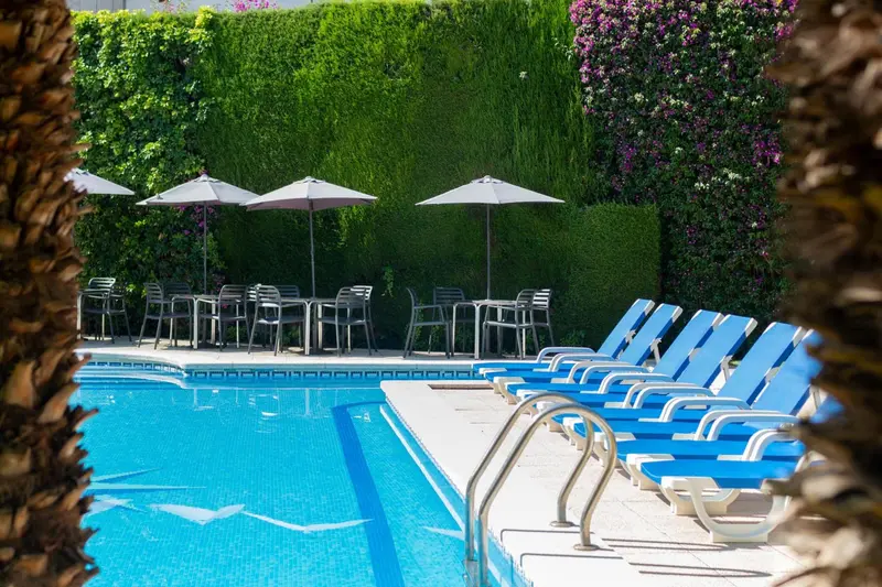 Transats bleus alignés au bord d'une piscine ensoleillée.