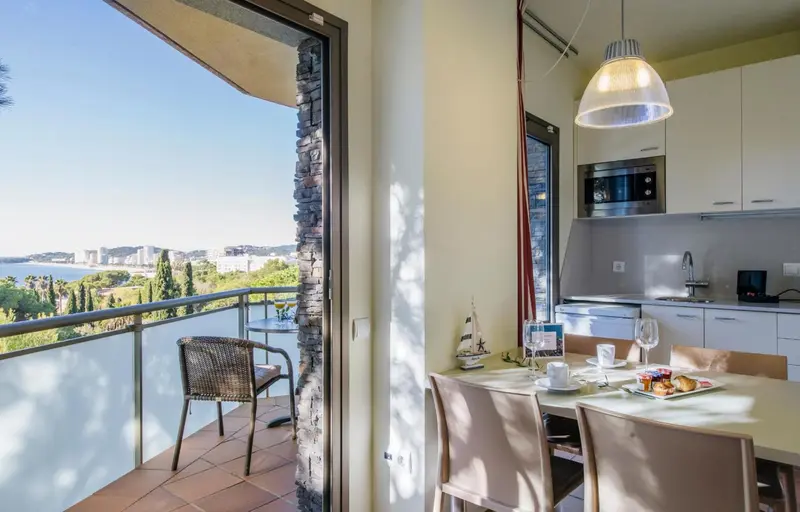 Une pièce lumineuse s'ouvre sur un balcon avec vue sur la mer.
