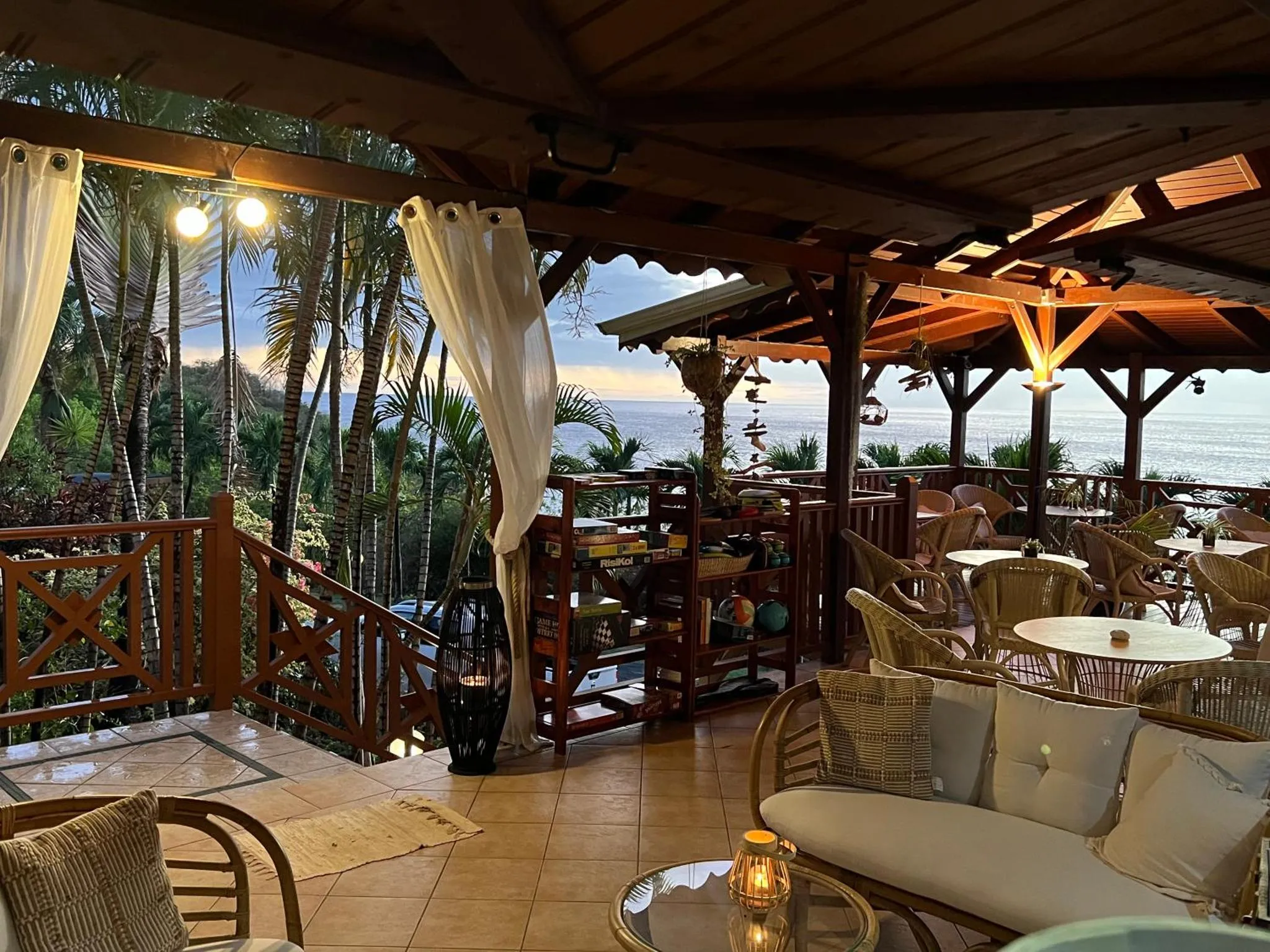 Terrasse ombragée avec mobilier de détente et vue sur la mer.