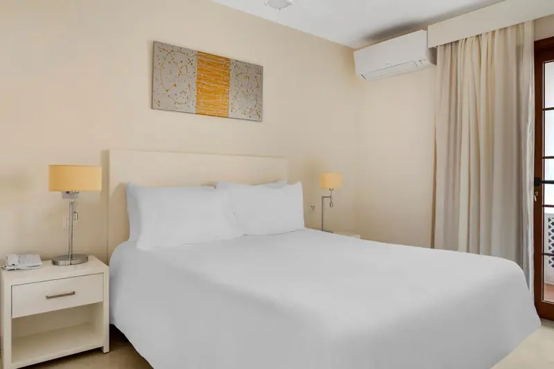 Une chambre lumineuse avec un grand lit blanc et une décoration murale.
