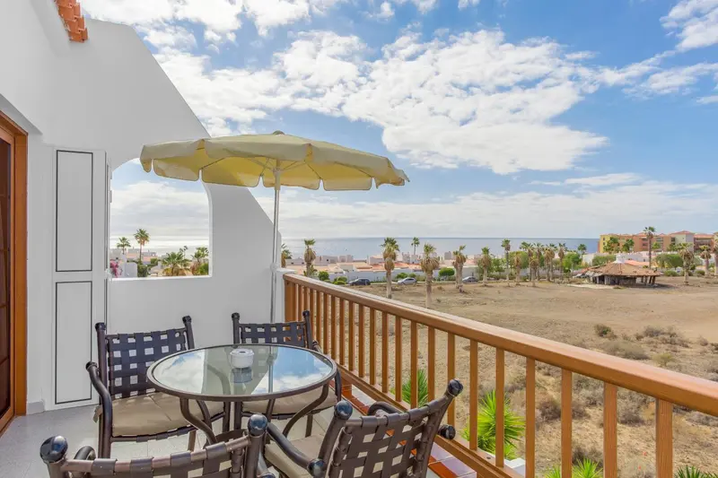 Terrasse avec mobilier de jardin et vue sur la mer et la ville.