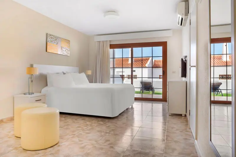 Une chambre lumineuse avec un grand lit et un accès à une terrasse.