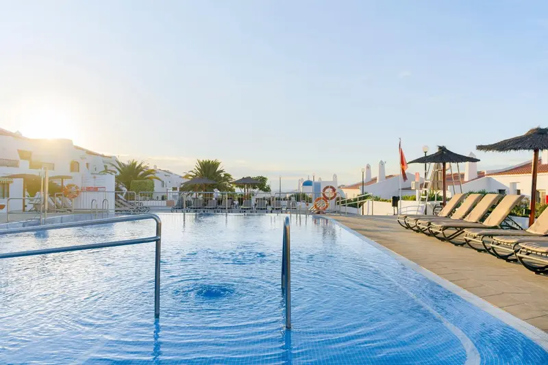 Une piscine rectangulaire avec des transats et des parasols au bord.