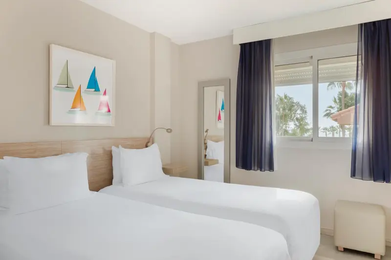 Une chambre lumineuse avec un lit double et une vue sur la végétation.