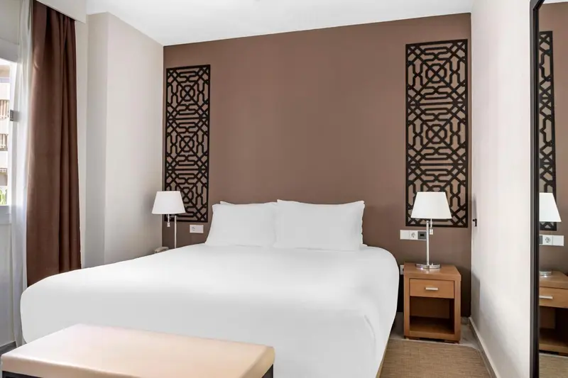 Une chambre d'hôtel avec un grand lit blanc et des tables de chevet.