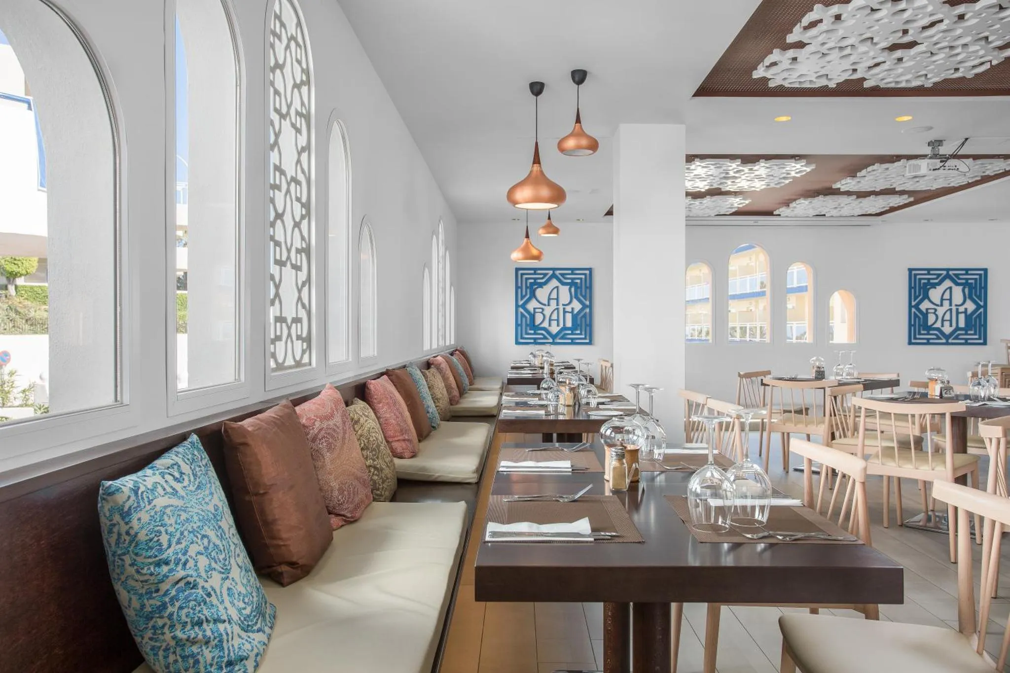 Une salle de restaurant lumineuse avec des banquettes et des tables dressées.