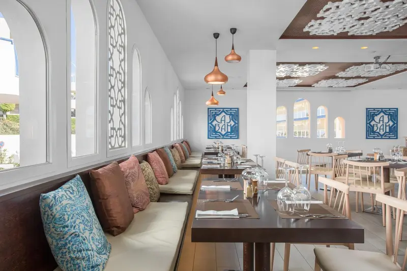 Une salle de restaurant lumineuse avec des banquettes et des tables dressées.
