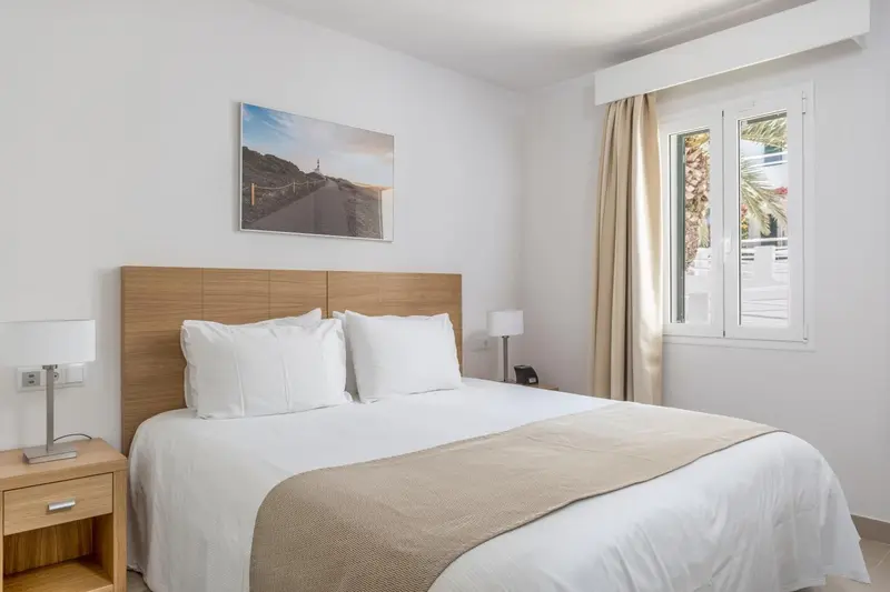 Une chambre lumineuse avec un grand lit recouvert d'une courtepointe et d'oreillers blancs.