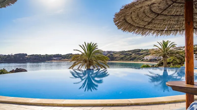 Une piscine à débordement surplombe une crique et la mer.