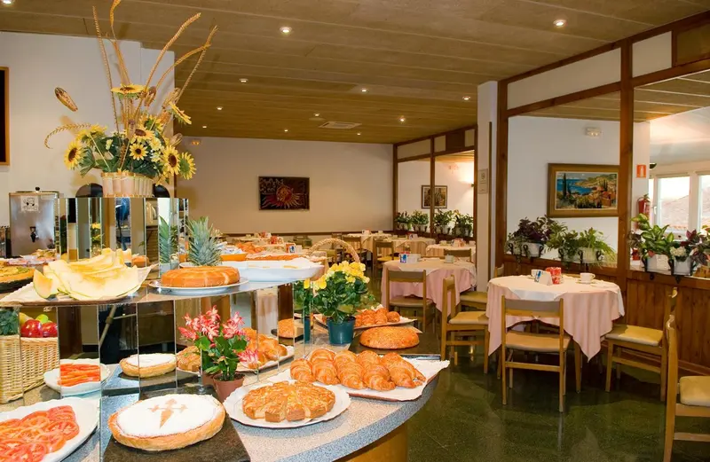 Un buffet de pâtisseries et de fruits est présenté dans une salle lumineuse avec des tables nappées.
