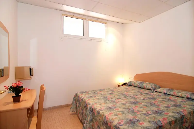 Une chambre lumineuse avec un lit et une coiffeuse.