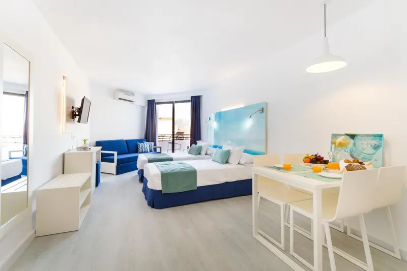Une chambre lumineuse avec un coin repas et un canapé bleu.