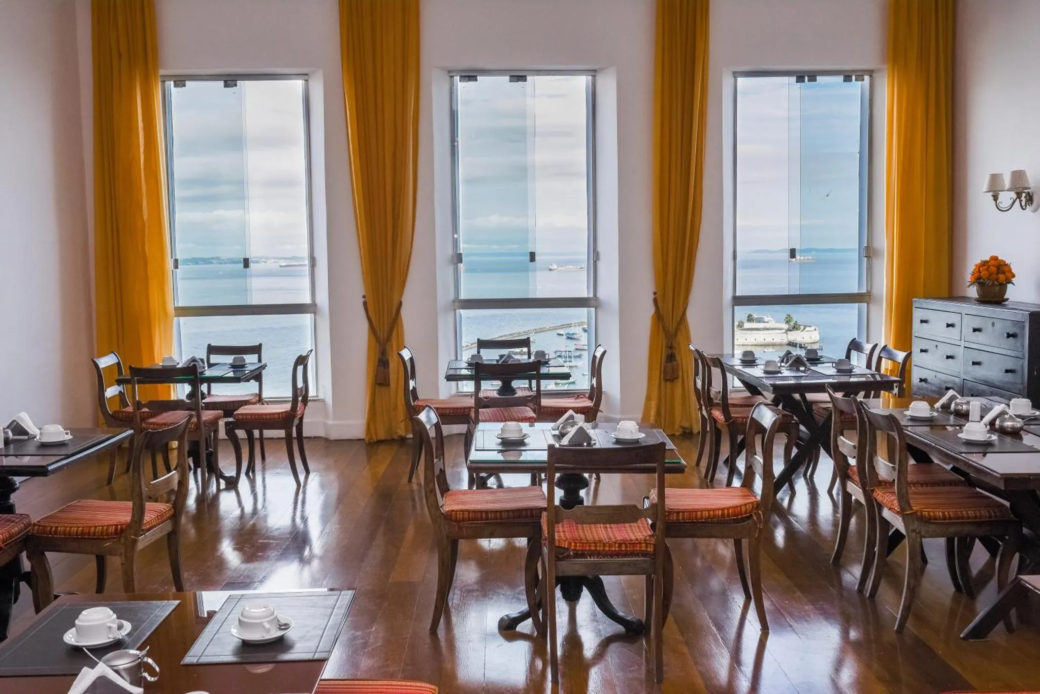 Une salle lumineuse avec des tables et des chaises donnant sur la mer.