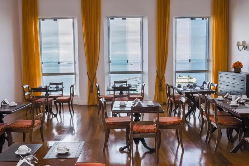 Une salle lumineuse avec des tables et des chaises donnant sur la mer.