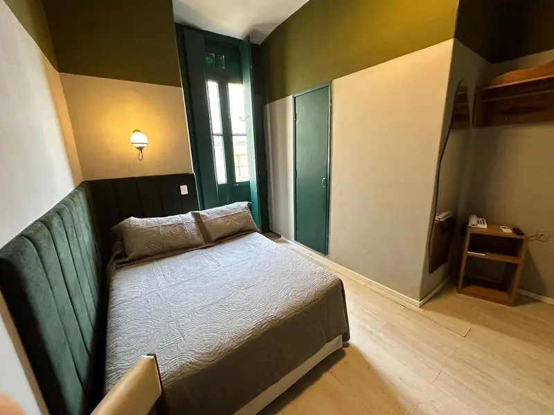 Une chambre avec un lit double et une commode en bois.