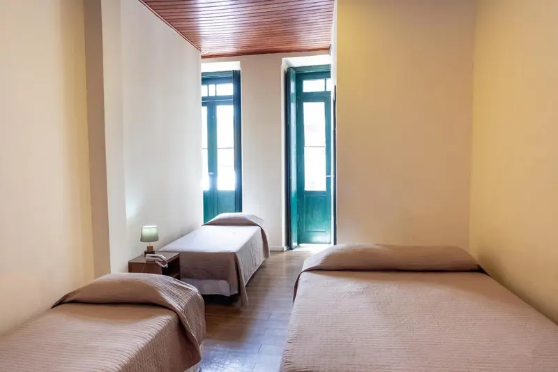 Une chambre lumineuse avec deux lits simples et une commode.