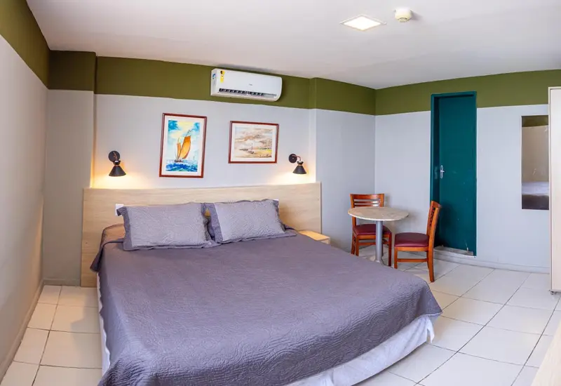 Une chambre lumineuse avec un grand lit et une petite table.