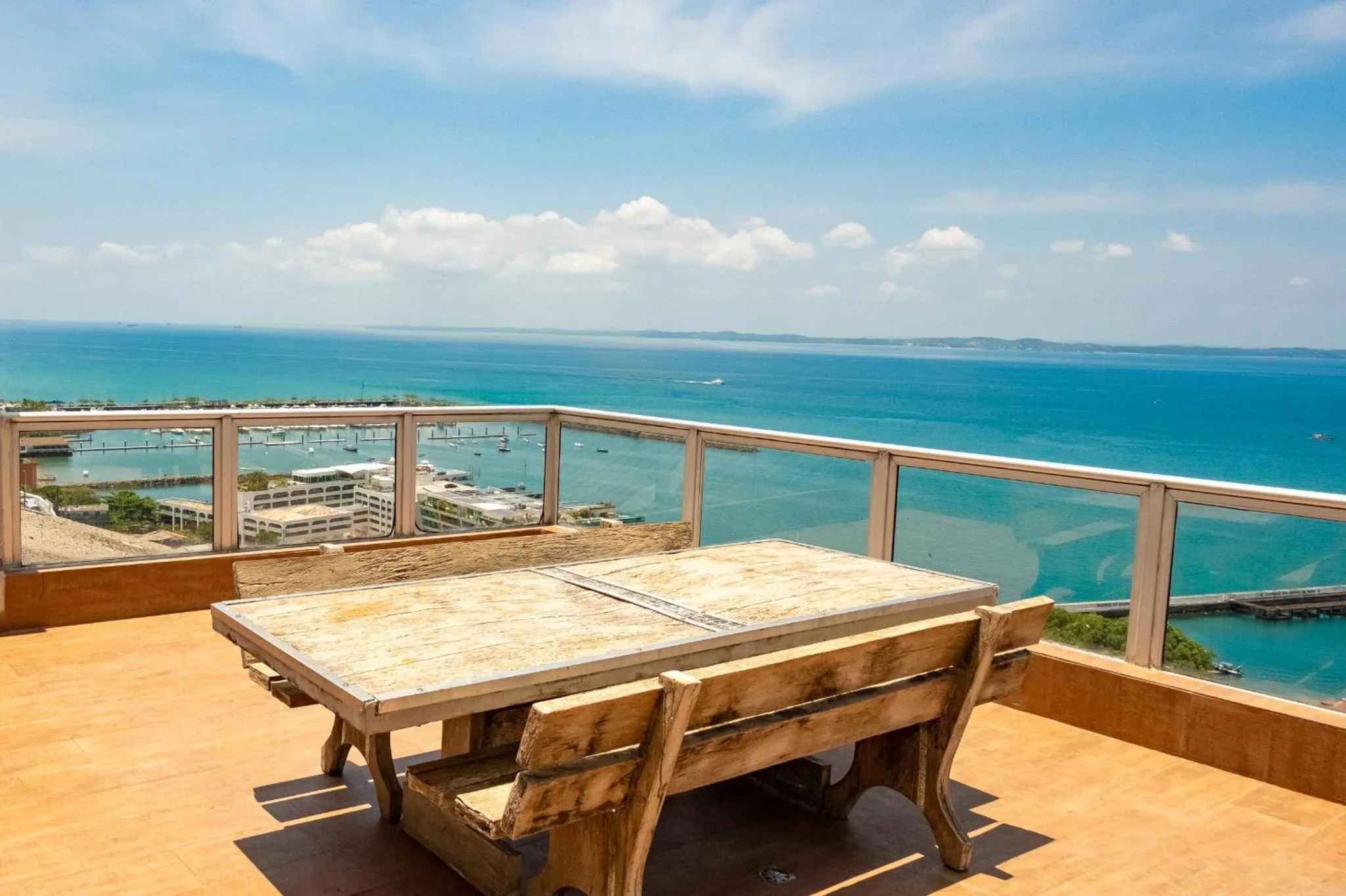 Une table et des bancs en bois sur une terrasse avec vue sur la mer.