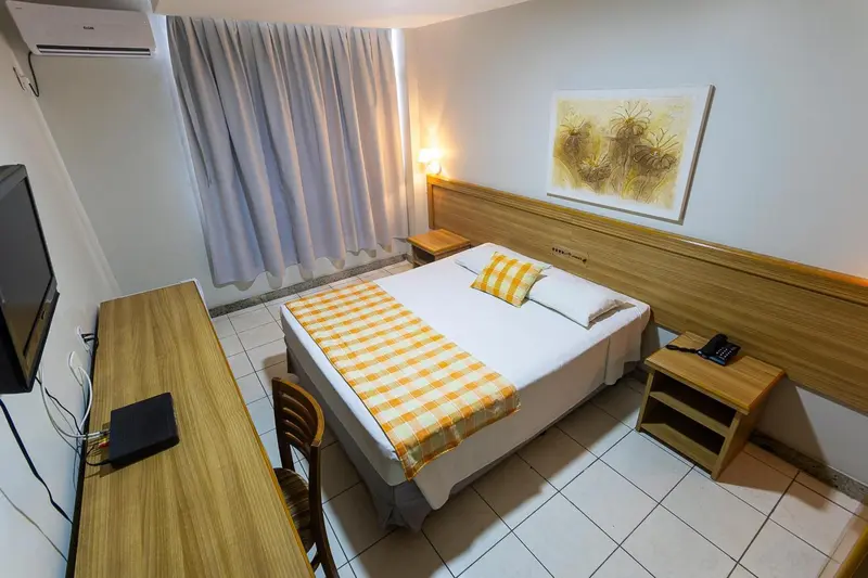 Une chambre lumineuse avec un lit recouvert d'une courtepointe à carreaux.