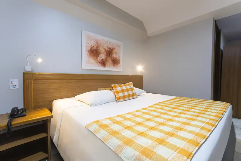 Une chambre lumineuse avec un grand lit recouvert d'une courtepointe à carreaux.