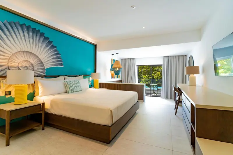 Une chambre lumineuse avec un grand lit et un décor mural coloré.