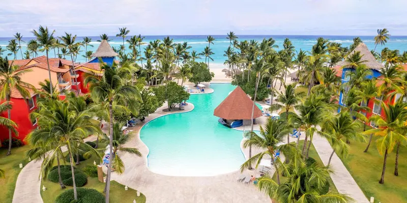 Vue aérienne d'un complexe hôtelier tropical avec piscine et végétation luxuriante.
