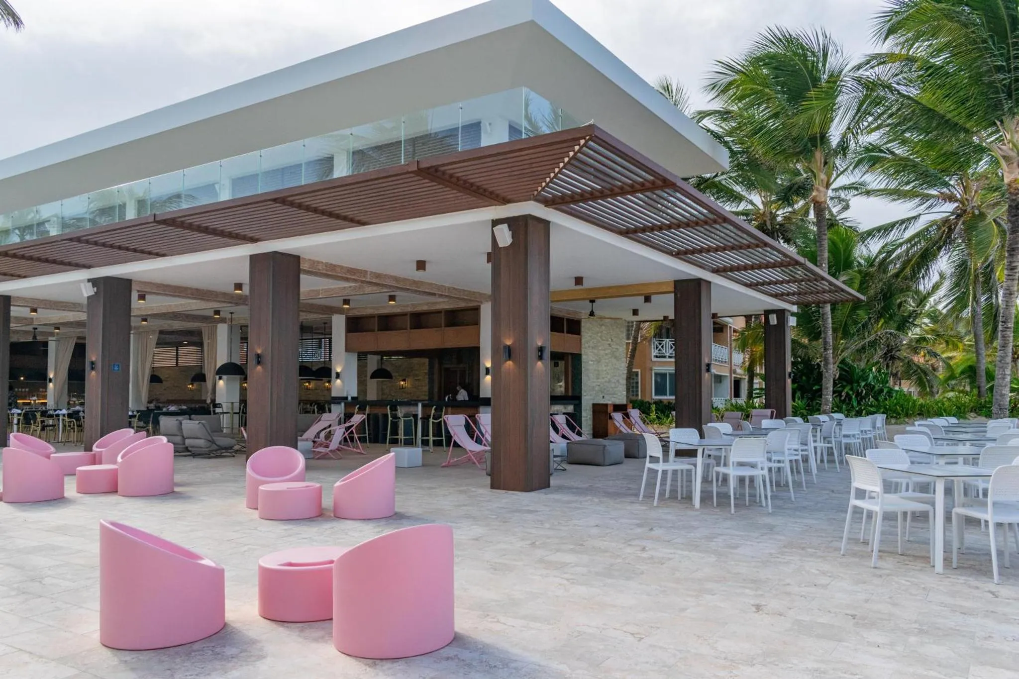 Terrasse ombragée avec mobilier de détente et tables à manger.