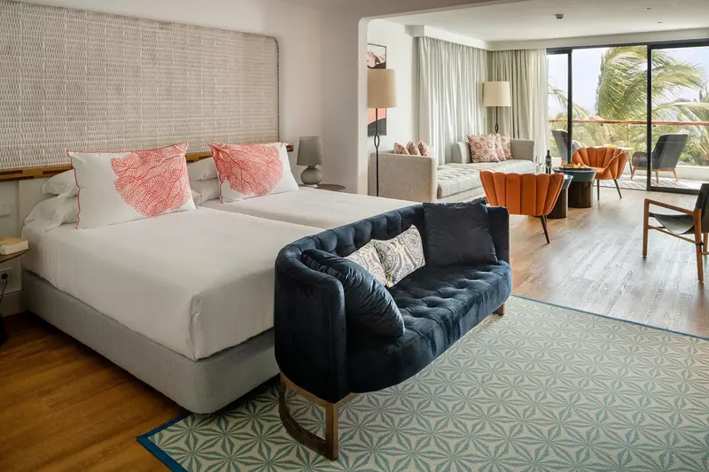 Une chambre lumineuse avec un grand lit et un coin salon.