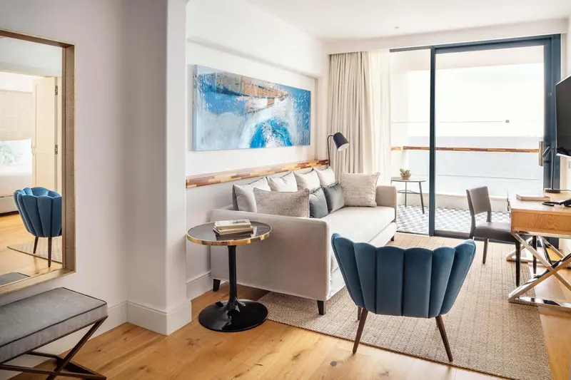 Espace de séjour lumineux avec canapé, fauteuils et vue sur l'extérieur.