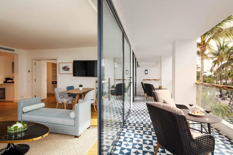 Espace de vie lumineux avec canapé, table et accès à une terrasse.