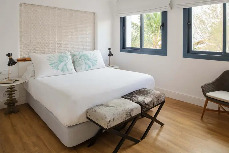 Une chambre lumineuse avec un grand lit recouvert de linge blanc.