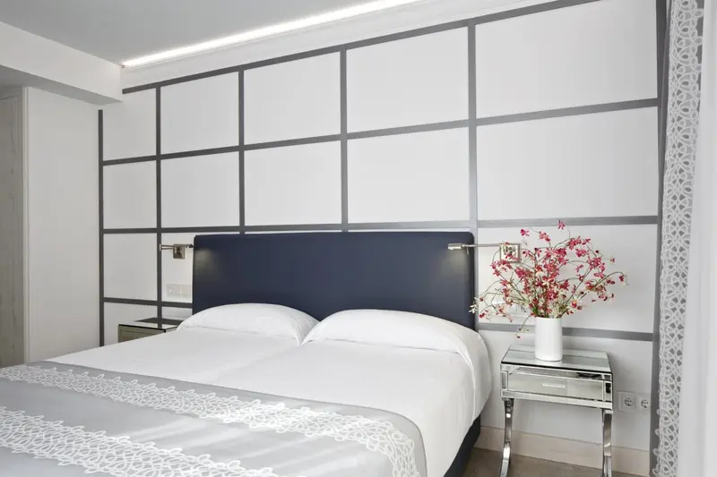 Une chambre lumineuse avec un grand lit recouvert d'une courtepointe blanche et de coussins.