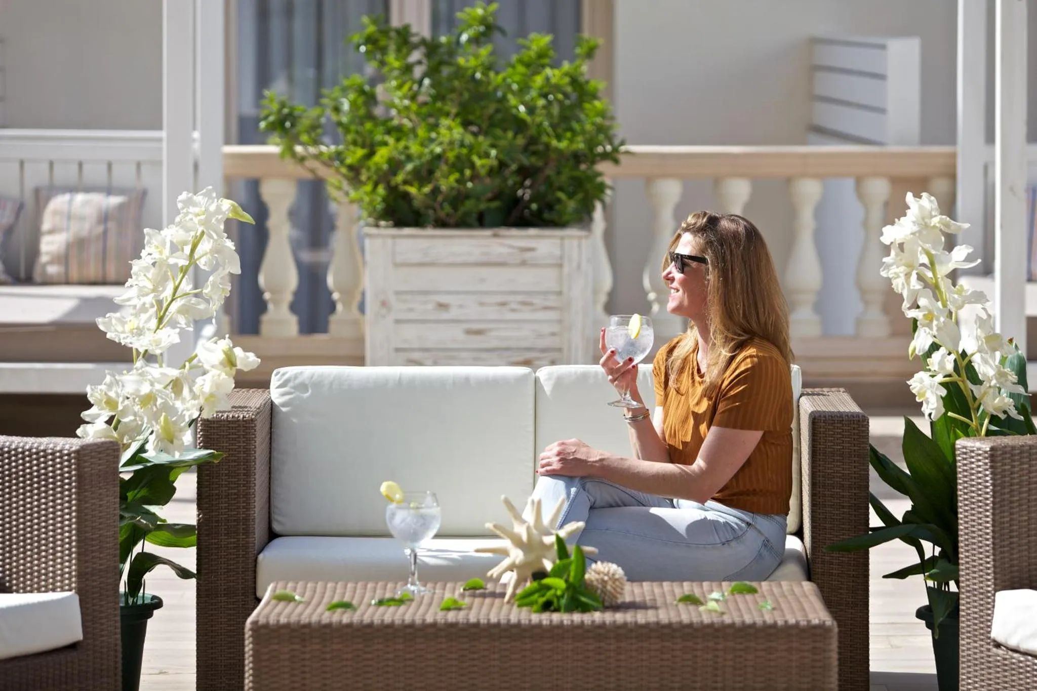 Une femme assise sur un canapé en extérieur déguste une boisson.