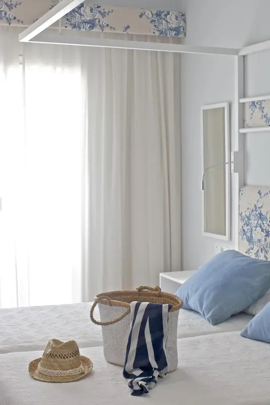 Une chambre lumineuse avec un lit recouvert de textiles clairs et un panier en osier.