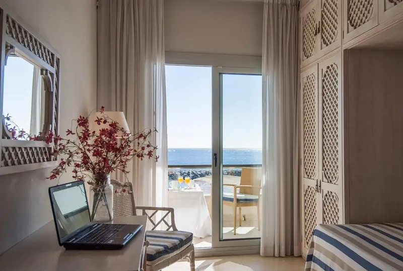 Une chambre lumineuse avec vue sur la mer depuis un balcon.