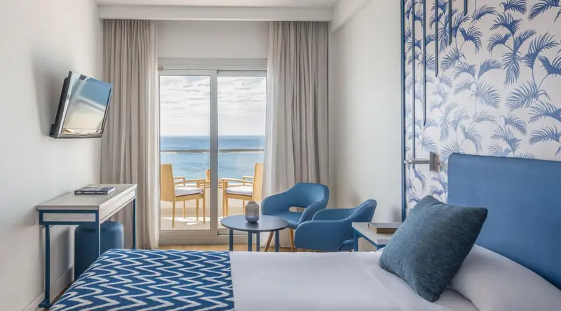 Une chambre lumineuse avec un balcon donnant sur la mer.