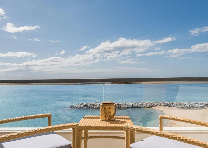 Terrasse avec mobilier en rotin donnant sur une plage et la mer.