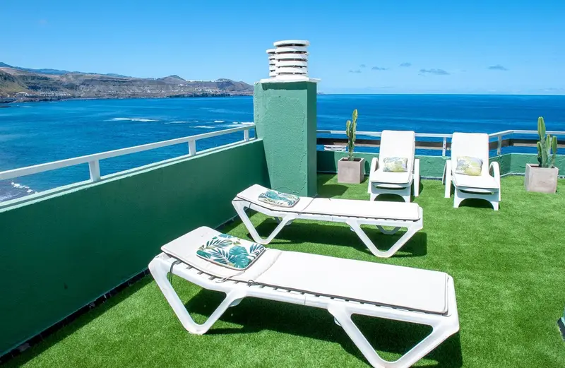 Terrasse avec transats et vue sur la mer.