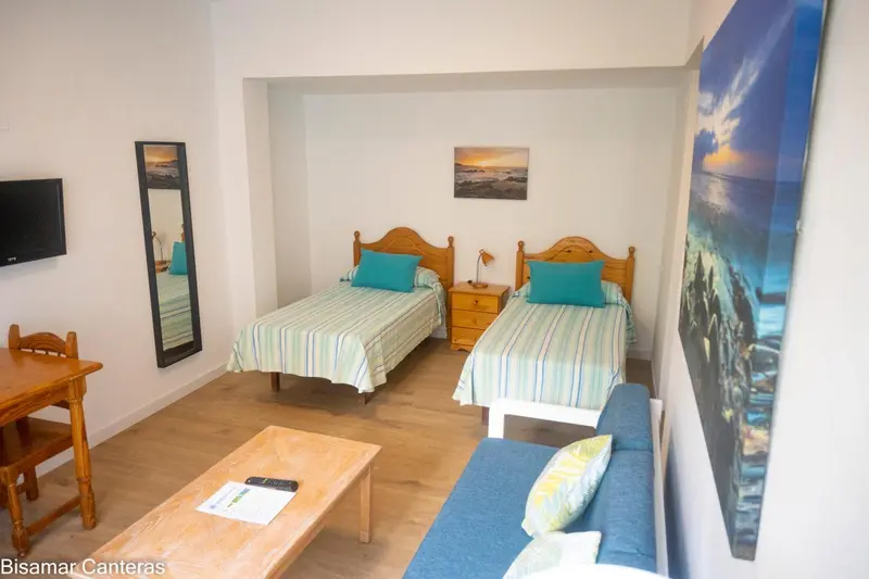 Une chambre lumineuse avec deux lits simples et un coin salon.