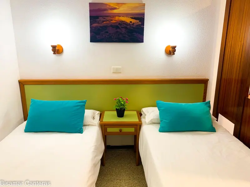 Une chambre avec deux lits simples et une décoration murale colorée.