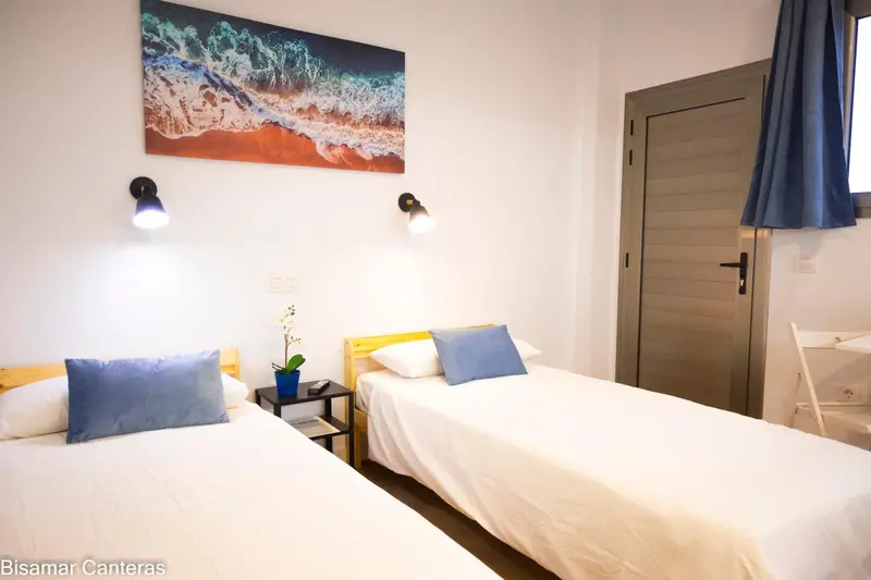 Une chambre lumineuse avec deux lits simples et une décoration murale abstraite.
