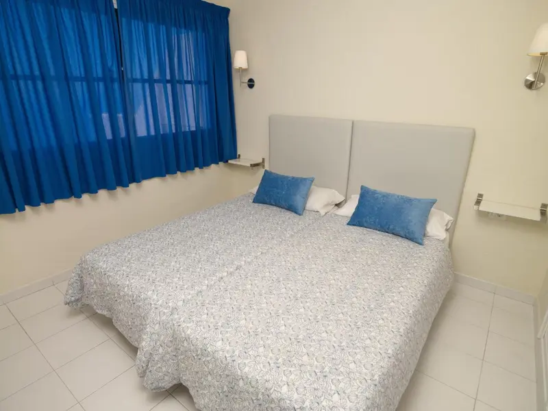 Une chambre lumineuse avec un grand lit recouvert d'une courtepointe.