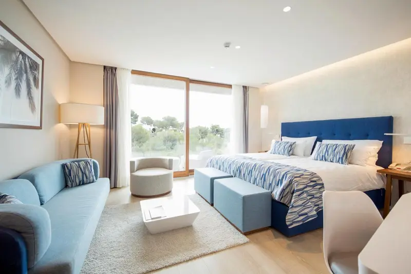 Une chambre lumineuse avec un canapé bleu et un grand lit.
