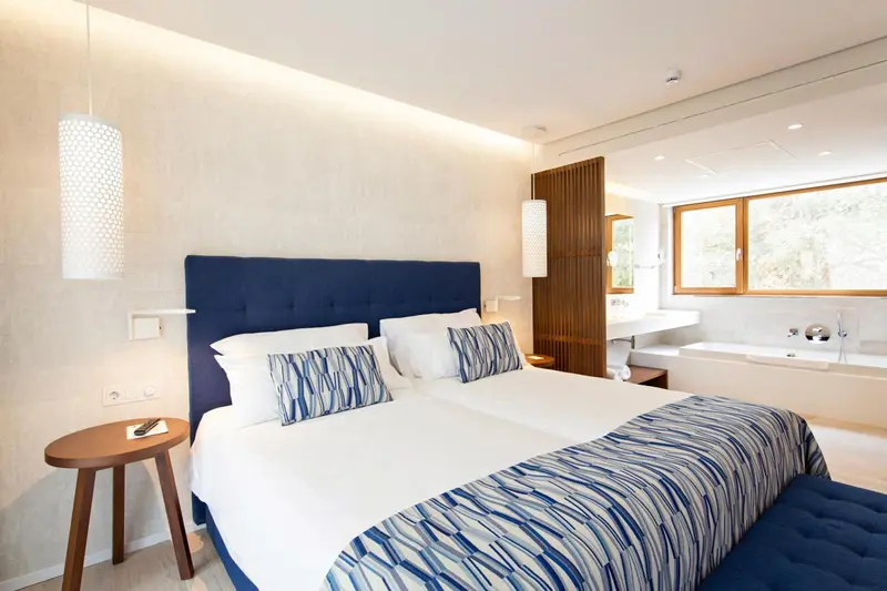Une chambre lumineuse avec un grand lit recouvert d'une couette à motifs.