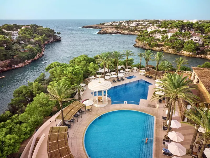 Vue aérienne d'une piscine entourée de végétation et donnant sur la mer.